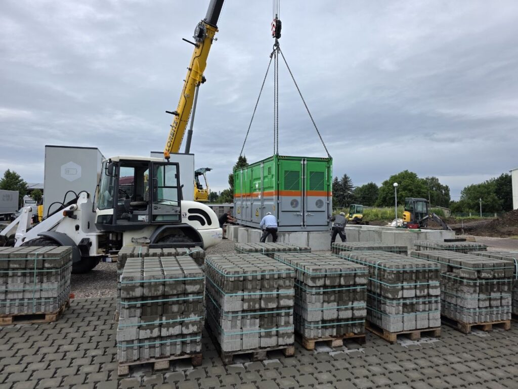 Ein grüner Speichercontainer hängt am Kran